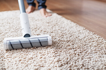 The turbo brush of a cordless vacuum cleaner cleans the carpet in the house With a clean stripe