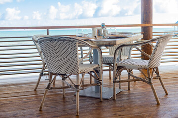 BEACH RESTAURANT TABLE WITH THE SEA IN THE BACKGROUND AND THE BLUE SKY ON TERRACE WITH WOODEN FLOOR