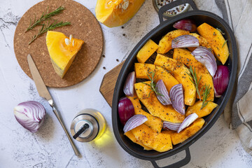 Raw pumpkins slice with rosemary and purple onion, baking fresh healthy food with spice on a gray stone background. Keto or paleo diet veggie vegan or vegetarian. Top view flat lay background.