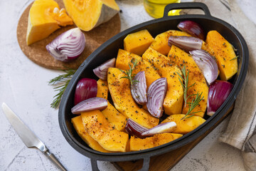 Raw pumpkins slice with rosemary and purple onion, baking fresh healthy food with spice on a gray stone background. Keto or paleo diet veggie vegan or vegetarian.