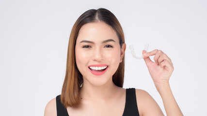 Obraz na płótnie Canvas Young smiling woman holding invisalign braces in studio, dental healthcare and Orthodontic concept