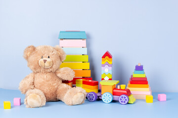 Kids toys collection. Teddy bear, wooden train, rainbow color xylophone and baby toys on light blue background. Front view