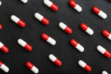 A pattern of red and white pill capsules on a black background background.