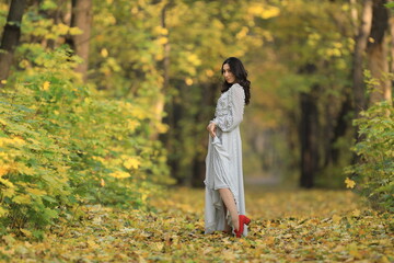 portrait of a beautiful young woman in a white dress in the autumn forest