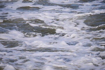 close up of the white foaming waves of the north sea when they hit the beach