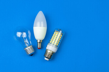 From old to new, fluorescent and LED light bulbs together, blue background. Energy saving concept. Flat lay, top view photo