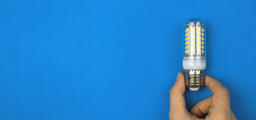 Hand with LED light bulbs, blue background. Flat lay, top view, copy space photo