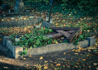 stary drewniany powalony krzyż na cmentarzu