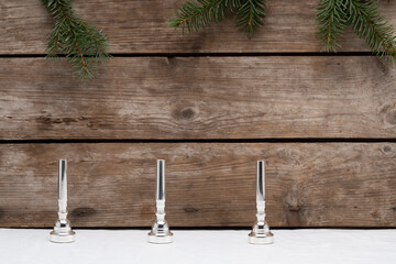 Three trumpet mouthpieces representing the third advent on a wooden background with some small pine tree branches