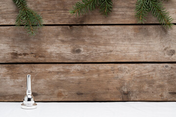 One trombone mouthpiece representing the first advent on a wooden background with some small pine tree branches