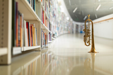 A raw brass rotary trumpet standing on its bell on a reflective light colored floor in the library...