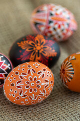 Homemade handmade wax and painted Easter eggs jute textile beige background, Eastertime decoration, five objects