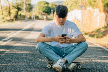 Obraz premium teenage boy with mobile phone and skateboard on the road