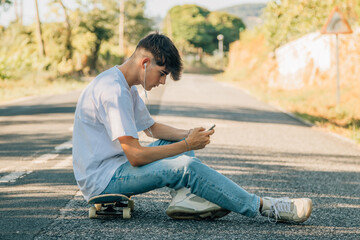 Fototapeta na wymiar teenage boy with mobile phone and skateboard on the road