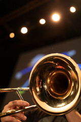 A person playing a trombone with stage lights in the back