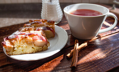 apple pie with cinnamon, served on a wooden tray with aromatic tea and cinnamon sticks