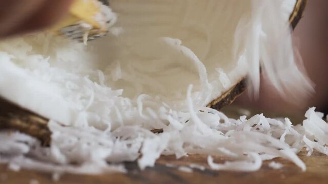 Old lady grating inside of coconut with grater. Making of shredded coconut for making food menu and dessert. Making of Stuffed Dough Pyramid Dessert called Ka-Nhom-Tian. Thai dessert menu.