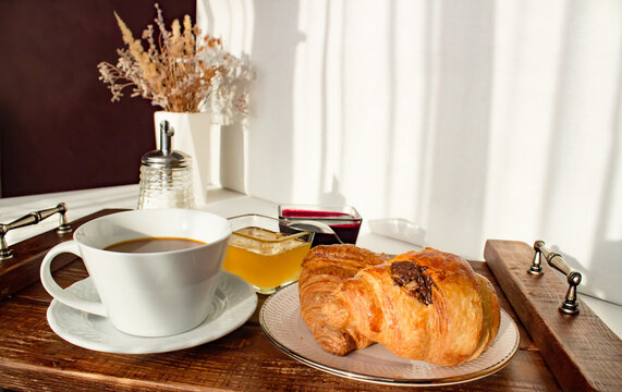 Crussans with chocolate, served with coffee, jam and honey on a wooden tray, breakfast.