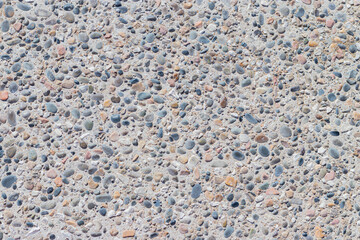 Background of multi-colored pebbles on the seashore. Sea stones of various sizes cover the sea coast. Pebble texture. Concept of natural background from stones. The surface of the rocky beach.