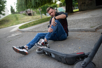 A man who fell from an electric scooter and is holding his knee © Razoran