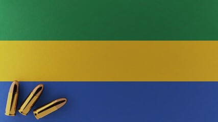 Three 9mm bullets in the bottom left corner on top of the national flag of Gabon