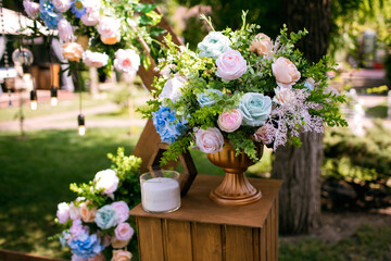 Naklejka na ściany i meble A vase of flowers as a decorative element for a wedding ceremony. Multicolored roses and candles at the wedding ceremony