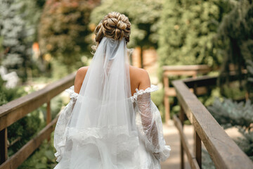Bride in a white wedding dress and veil with a beautiful hairstyle back view. Cute blonde bride...