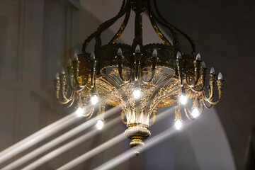 A beautiful metal chandelier in a church with lights and directional light streaks caused by a glass prism