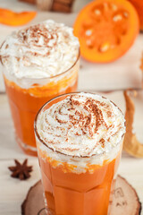 Pumpkin latte with whipped cream on light wooden background. Hot spicy smoothie. Vegetable vegan drink.