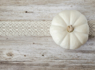 A white pumpkin and crochetted ivory lace on wood background
