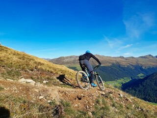 Enduro ride with steep bend, banked curve, Swiss Mountain Alps at Davos Switzerland. With blue...