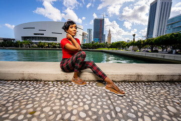Woman sitting by the water. Scene of DOwntown Miami blurred in the background