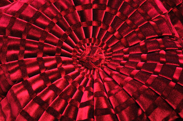 Red decorated plush pillow, macro concert circular element. Fabric sewn on embossed pleats with...
