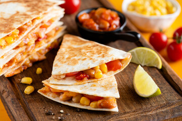 Vegetarian quesadilla with beans and tomatoes on wooden board, closeup view. Mexican cuisine food