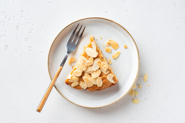 Slice of delicious almond cake on a plate, top view, grey stone background