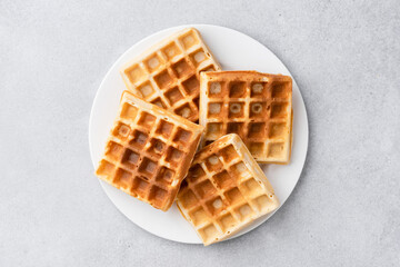 Square belgian waffles on plate isolated on grey background, top view