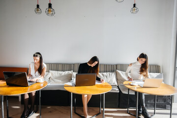 A group of young girls sit in an office and work at computers. Communication and training online.