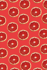 Ruby red grapefruit slice pattern on a coral red background, Flat lay, Summer fruit concept 