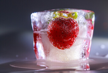 Frozen red sweet summer berries in ice. Cold freeze, winter background, frozen water.
