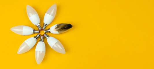 Home safety and electrical short circuit, failure concept. Broken and burn out LED light bulb after fire. Top view, banner with copy space, yellow background