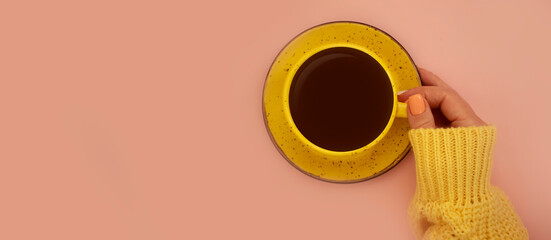 female hands hold a cup of coffee on a colored background