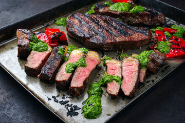 Traditional barbecue dry aged wagyu Brazilian picanha beef steaks served with chili and chimichurri sauce as close-up on a rustic tray
