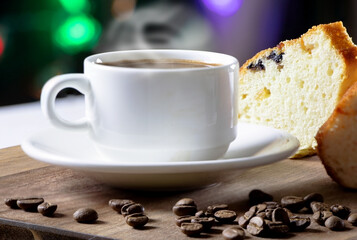 A cupcake with raisins and a cup of black coffee. English breakfast on a wooden background. Colorful blurred background.Pieces of muffin with raisins.