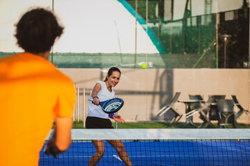 Young teacher is monitoring teaching padel lesson to his student - Coach teaches girl how to play...