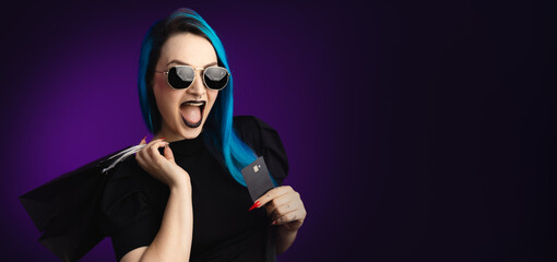 Large banner Woman in black friday, shopping, expressions with sunglasses, shopping bag and credit card in hand, blue hair, copy space, black background, neon style for websites, billboards and boards