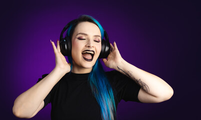 Fototapeta premium Large banner Woman in black friday, shopping, expressions, with headphones listening to music and dancing, blue hair, copy space, black background, neon style for websites, billboards and boards