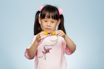 young girl holding traditional  Chinese moon cake against plain blue background