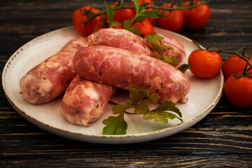 raw sausages, tomato on wooden background
