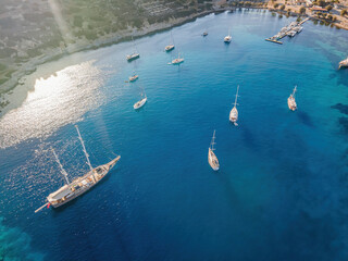 Sailing yachts anchored in the bay with clear and turquoise water on the sunset. Aerial drone view