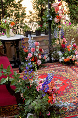 Fototapeta na wymiar decoration of a fotozone with natural flowers, eastern carpet and sofa